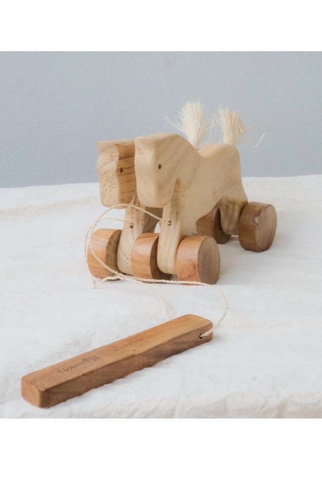 Wooden toy horse on wheels with a wooden stick on a light gray background